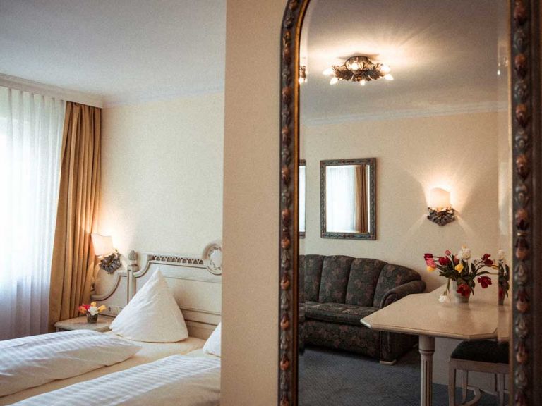 Sicht auf das Doppelbett und Ankleidespiegel im Hotel Limmerhof